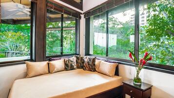 A bedroom with a bed, large windows, and a view of greenery.