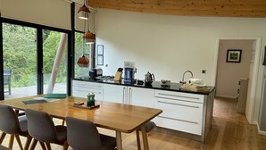 Una cocina moderna con una isla de madera, armarios blancos y un comedor con mesa y sillas de madera.