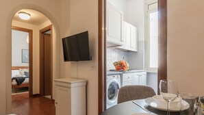 Una cocina moderna con armarios blancos, lavadora y comedor con mesa para dos.