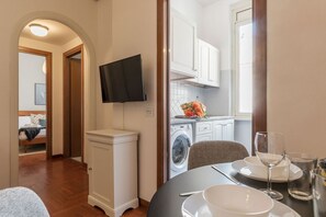 A modern kitchen with white cabinets, a washing machine, and a dining area with a table set for two.