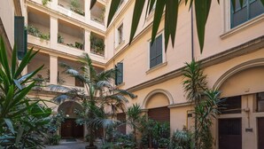 Un patio con varios balcones, plantas en macetas y un sendero adoquinado.