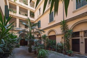 A courtyard with multiple balconies, potted plants, and a cobblestone path.