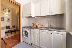 A compact kitchen with white cabinets, a built-in washing machine, and a sink.
