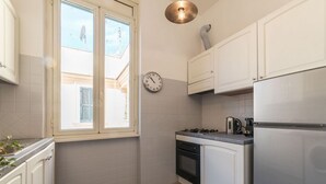 Una cocina con armarios blancos, estufa, refrigerador y un reloj en la pared.