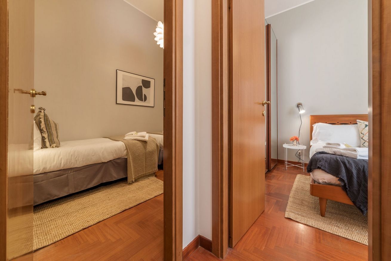 A bedroom with a bed, bedside table, and a small table with a lamp.