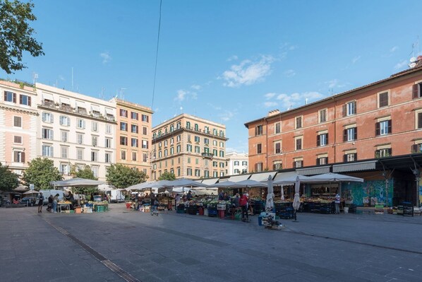 Una plaza con puestos de mercado al aire libre y edificios históricos al fondo.
