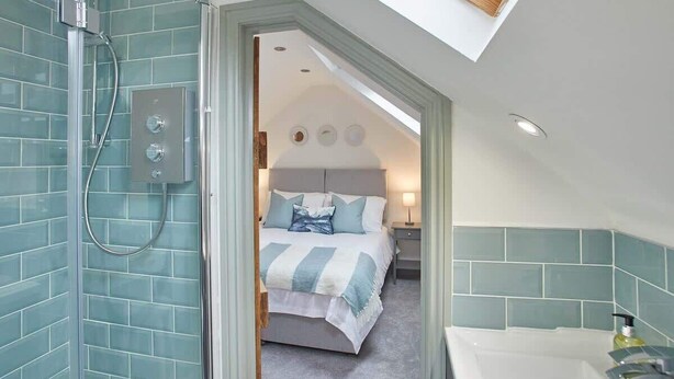 A modern bathroom with a shower, a bathtub, and a skylight. - Host & Stay | Threadneedle Cottage (Whitby)