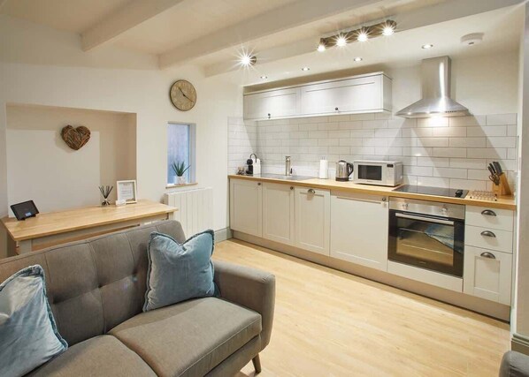 A modern kitchen with white cabinetry, a stainless steel range hood, and a built-in oven. - Host & Stay | Threadneedle Cottage (Whitby)
