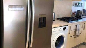 Eine Küche mit einem Edelstahl-Kühlschrank, einer Waschmaschine und einem Herd.