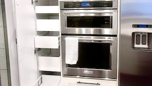 Una cocina con armarios blancos, un refrigerador de acero inoxidable y un horno empotrado.