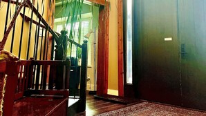 Un vestíbulo espacioso con una escalera de madera, una planta grande en maceta y una alfombra estampada.