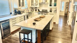 Una cocina moderna con armarios blancos, una isla central y una campana extractora de acero inoxidable.