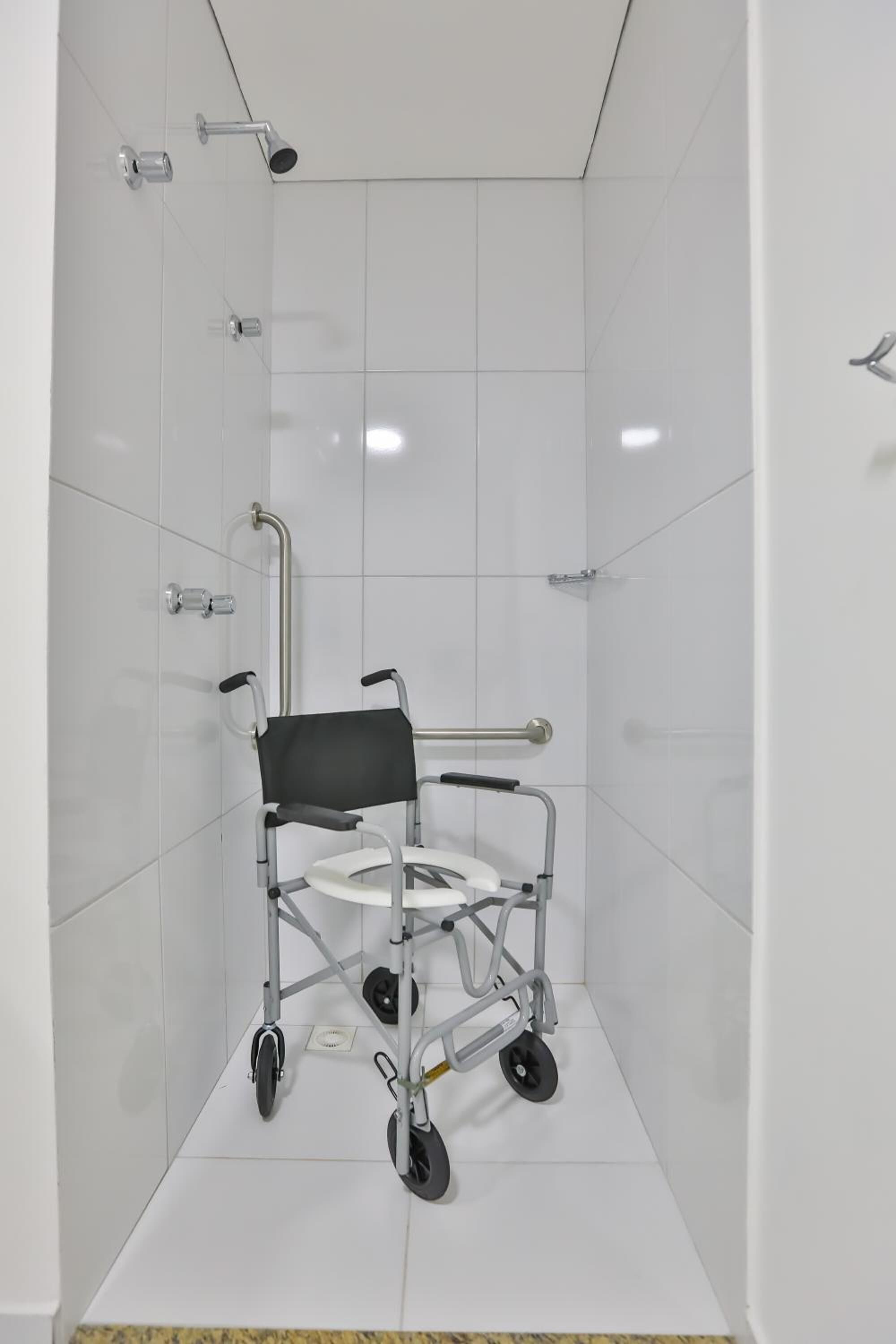 A wheelchair-accessible shower stall with a handheld showerhead, grab bars, and a non-slip floor.