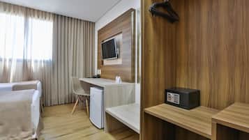 A hotel room with a bed, a desk, a television, a mini-fridge, and a sound system.