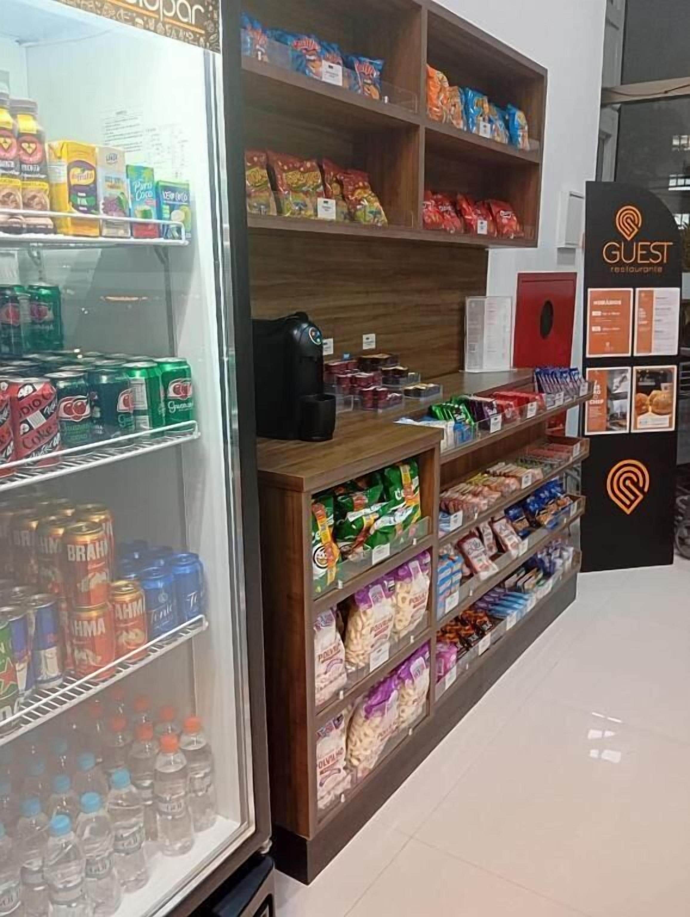 A snack and beverage display in a hotel lobby with various snacks, bottled water, and cans of beverages.