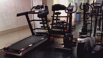 Un gimnasio con cintas de correr, elípticas y equipo de pesas.