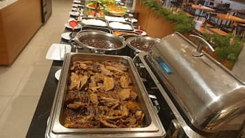 A buffet setup with various dishes and a large meat dish in the center.