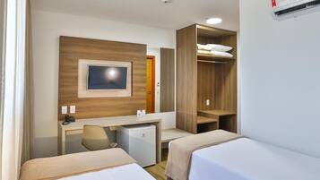 Habitación de hotel con dos camas, un escritorio, una silla, un televisor, un armario y aire acondicionado.