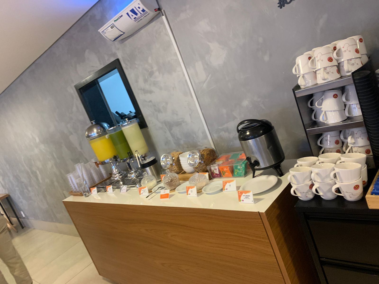 Um balcão com diversos itens, incluindo uma máquina de café, copos e recipientes de comida.