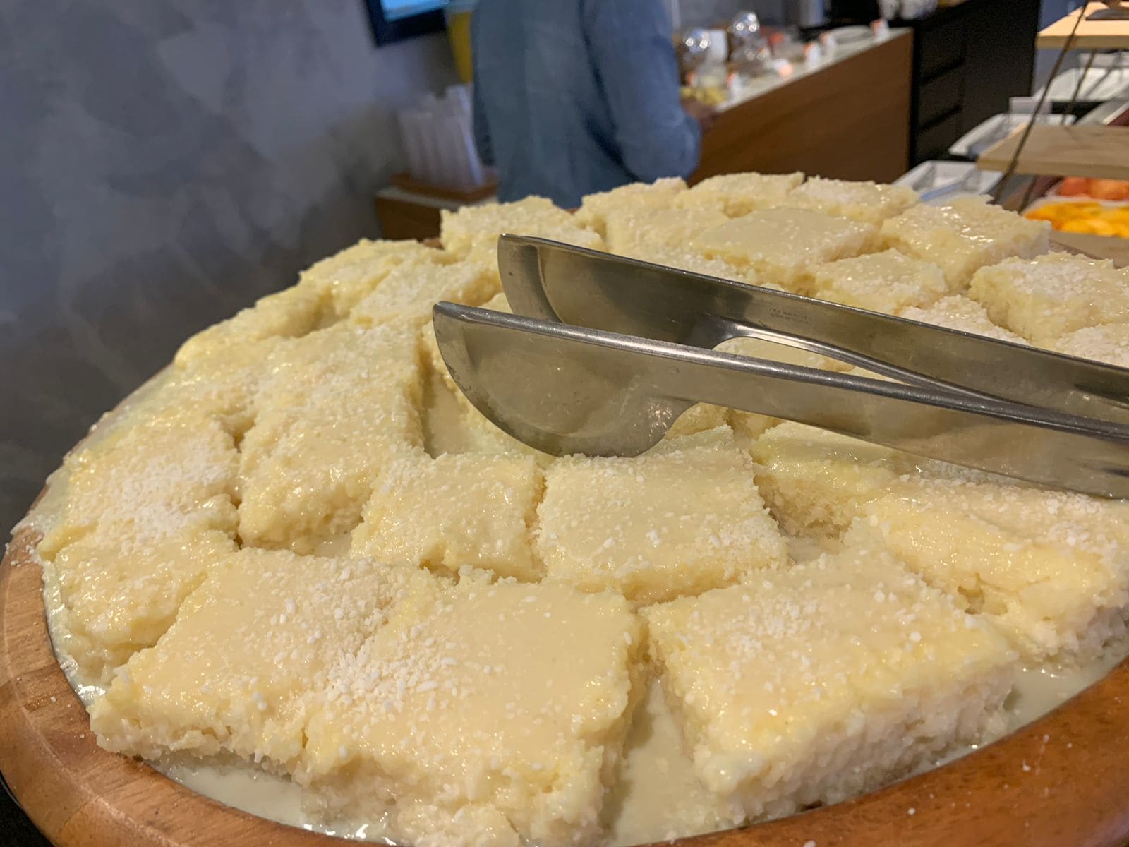 Un vassoio con dolci, dalla consistenza cremosa e friabile, forse una torta o un budino, su un tagliere di legno.