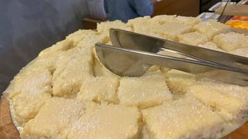 Un vassoio con dolci, dalla consistenza cremosa e friabile, forse una torta o un budino, su un tagliere di legno.