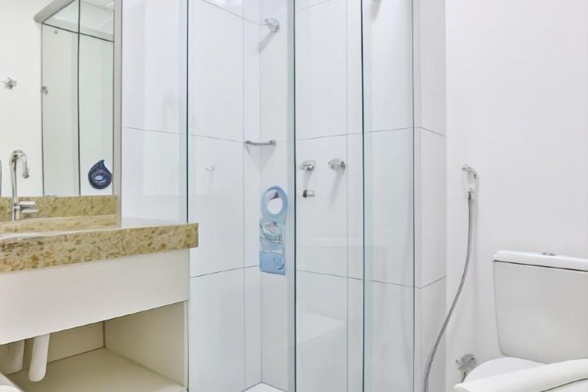 A modern bathroom with a glass shower enclosure, a white sink with a granite countertop, and a toilet.