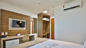 A hotel room with a bed, a desk with a computer, a TV, a wardrobe, and an air conditioning unit. - Nobile Inn Meridional Cariacica (Cariacica)