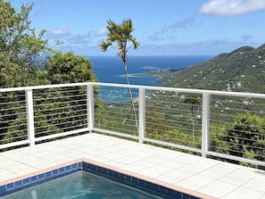 A pool area with a view of the ocean and hills.