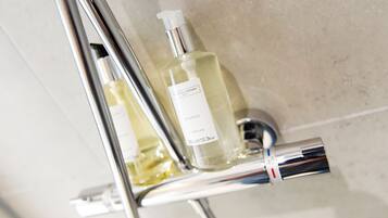 Un bagno con un rubinetto cromato e una bottiglia di shampoo.