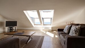 A spacious loft apartment with a high ceiling, skylights, a flat-screen TV, a sofa, and a coffee table. - Stables 2 -  a llyn peninsula that sleeps 2 guests  in 1 bedroom (Pwllheli)