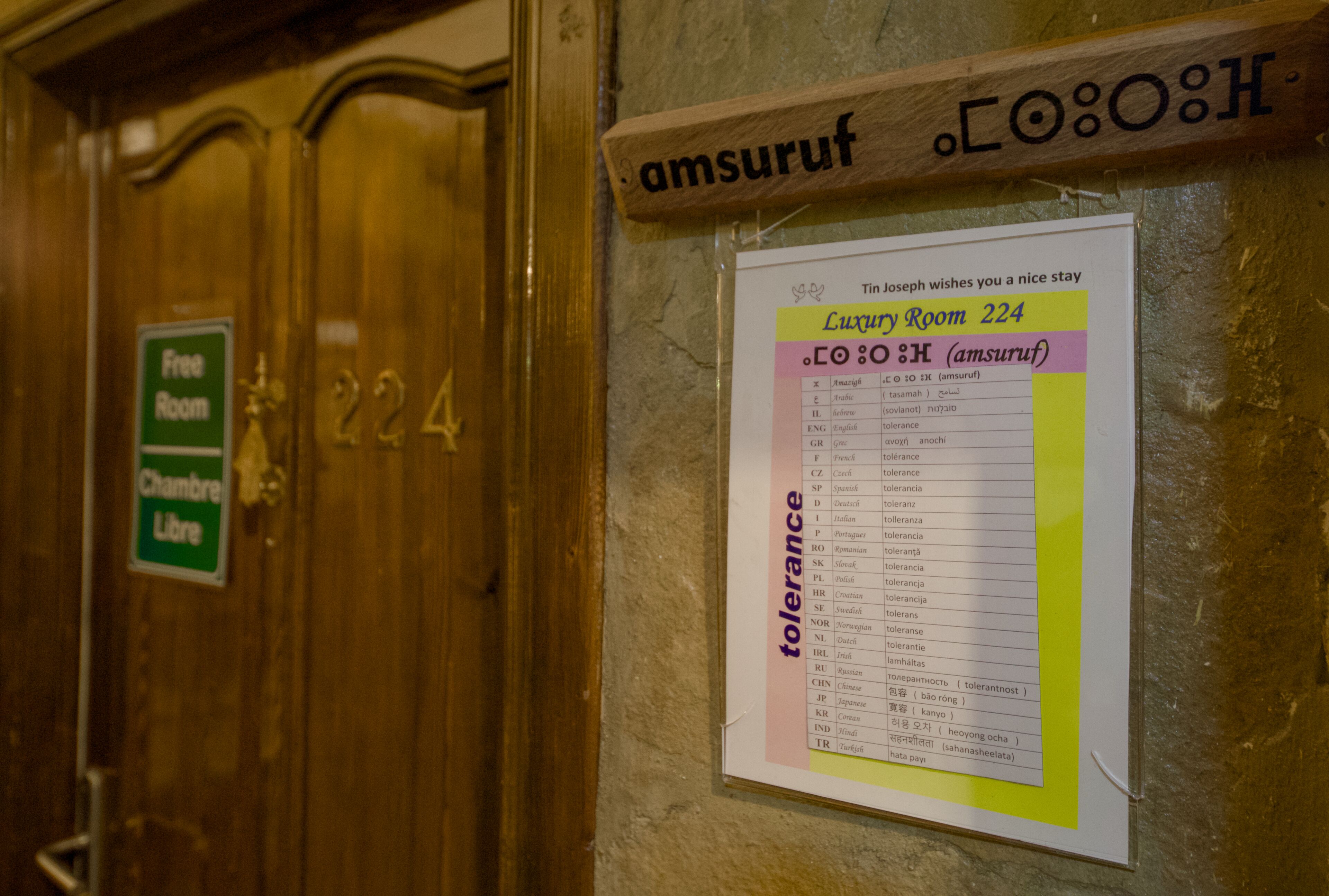 Puerta de una habitación de hotel con un cartel que indica que es gratuita y una lista de tolerancias en la pared.