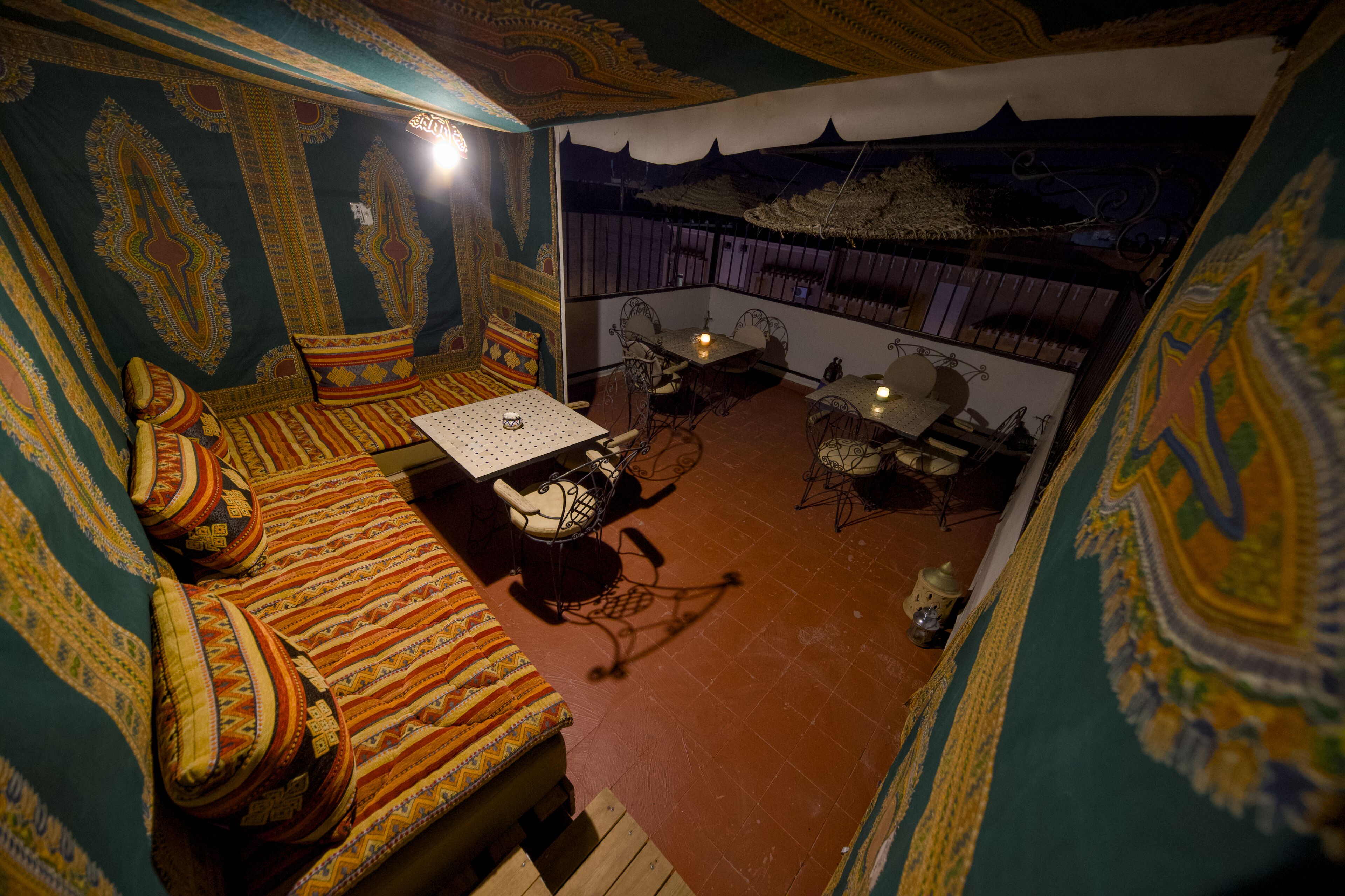 Une pièce avec un mur orné de motifs, un canapé avec des coussins, une petite table et une chaise.