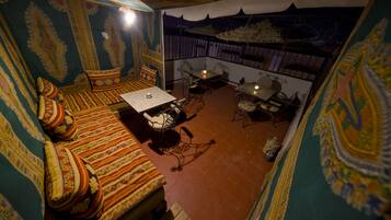 A room with a patterned wall, a sofa with cushions, a small table, and a chair.