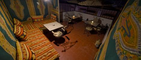 Une pièce avec un mur orné de motifs, un canapé avec des coussins, une petite table et une chaise.