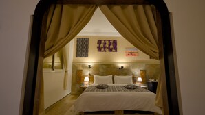 A bedroom with a bed, curtains, wall art, and bedside lamps. - Tin Joseph (Ouarzazate)