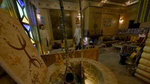 A room with a central fountain, a sofa set, and a wall with religious artwork. - Tin Joseph (Ouarzazate)