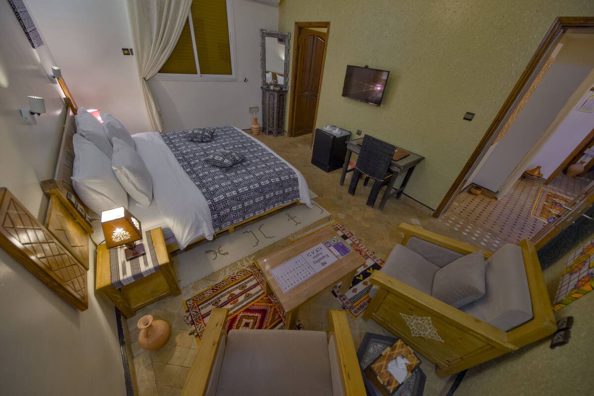 A hotel room with a bed, a desk, a chair, a television, and a small table.
