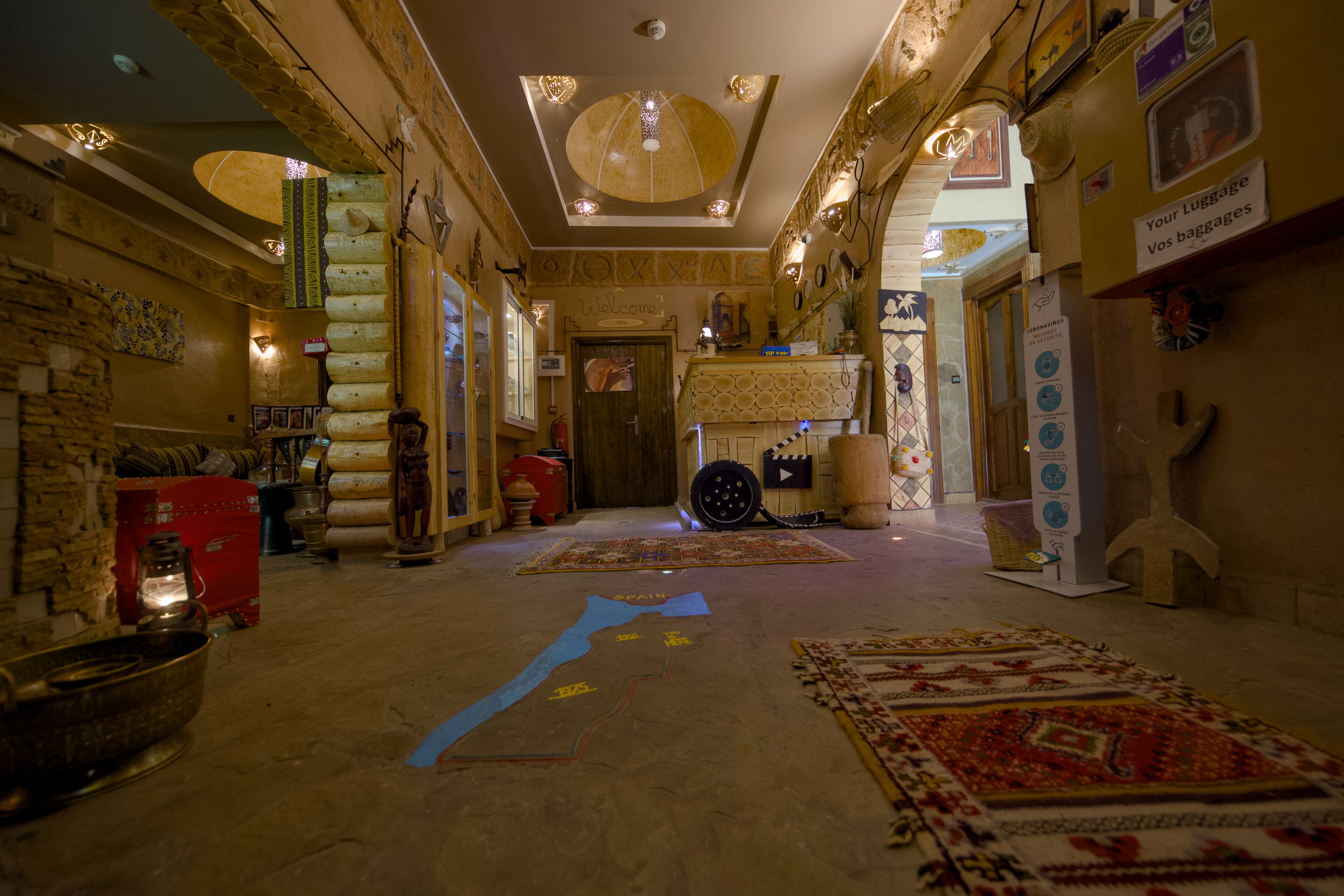 A spacious lobby with a central carpet design, a reception desk, and a variety of decorative items and furniture.