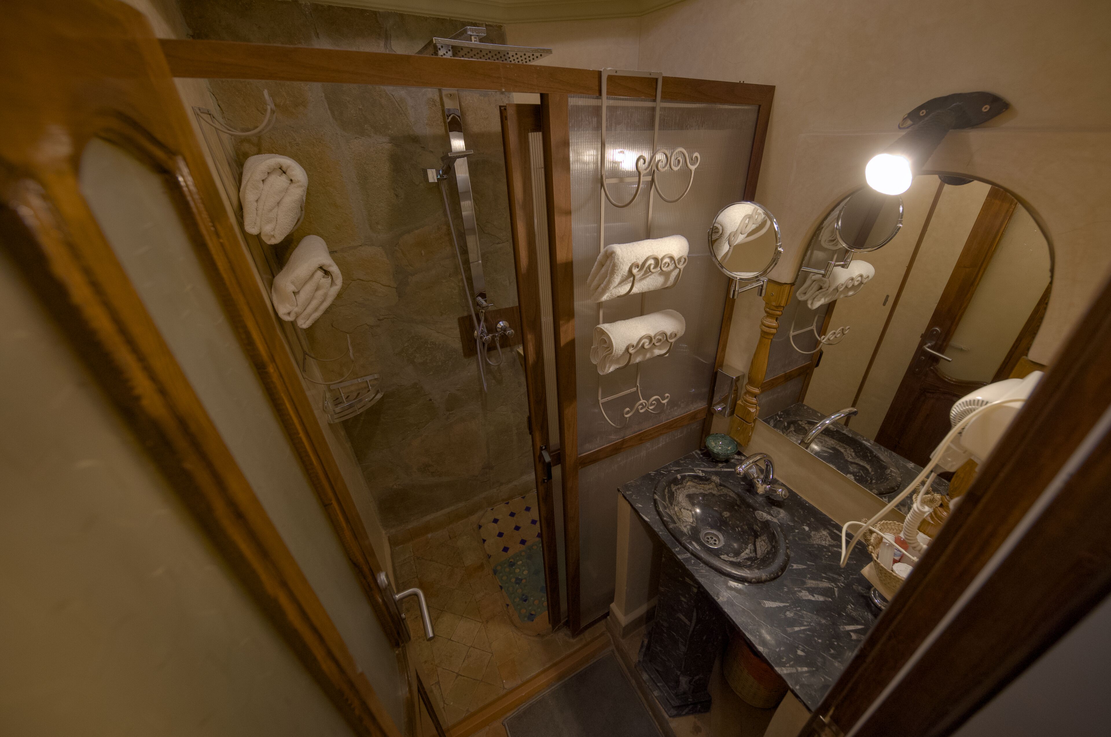 Une salle de bain avec une douche, un lavabo doté d’un plan de travail en marbre et des serviettes suspendues à un porte-serviettes.