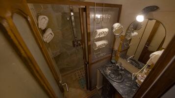 Une salle de bain avec une douche, un lavabo doté d’un plan de travail en marbre et des serviettes suspendues à un porte-serviettes.