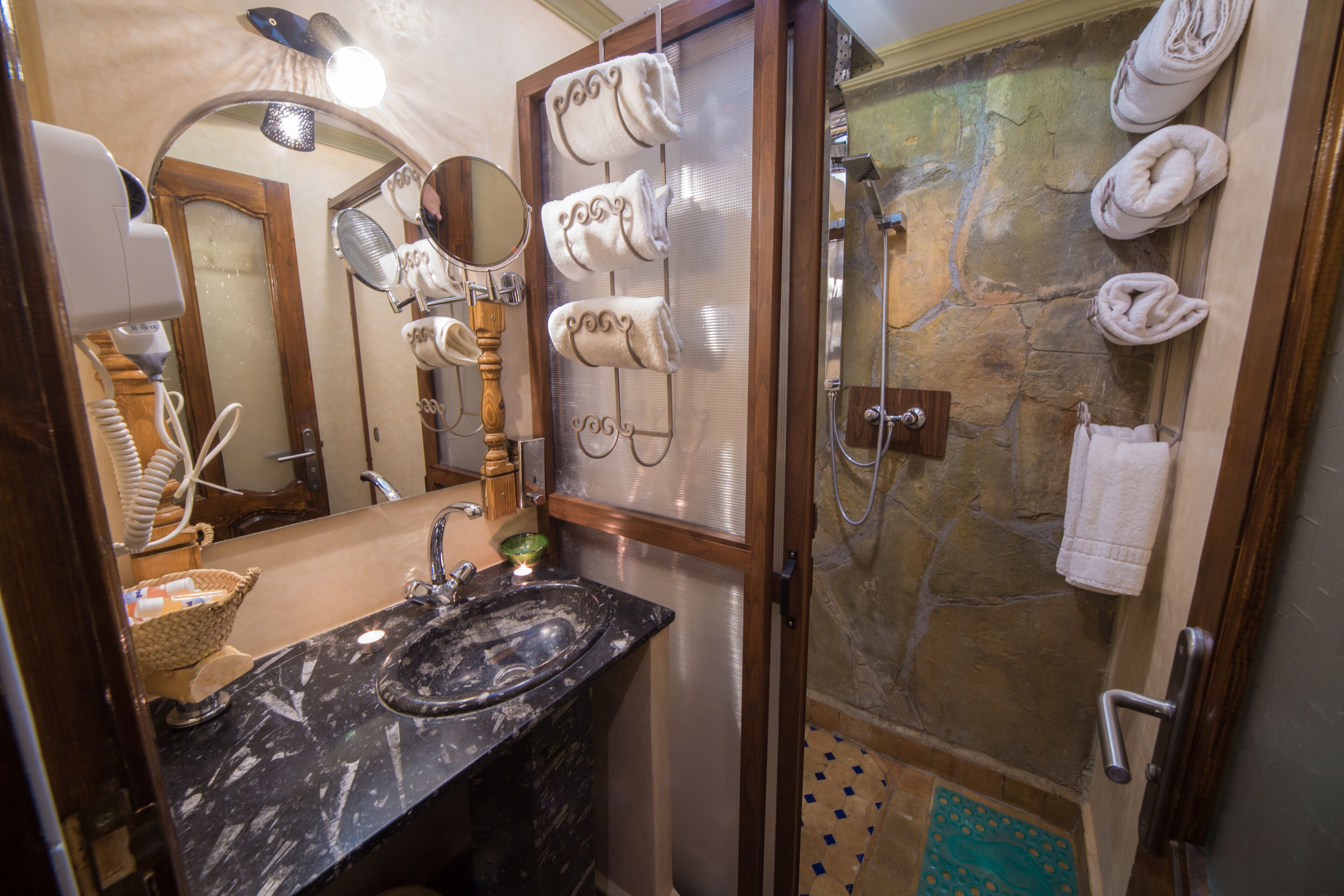 Un baño con lavamanos de mármol, un espejo, toallero y zona de ducha.