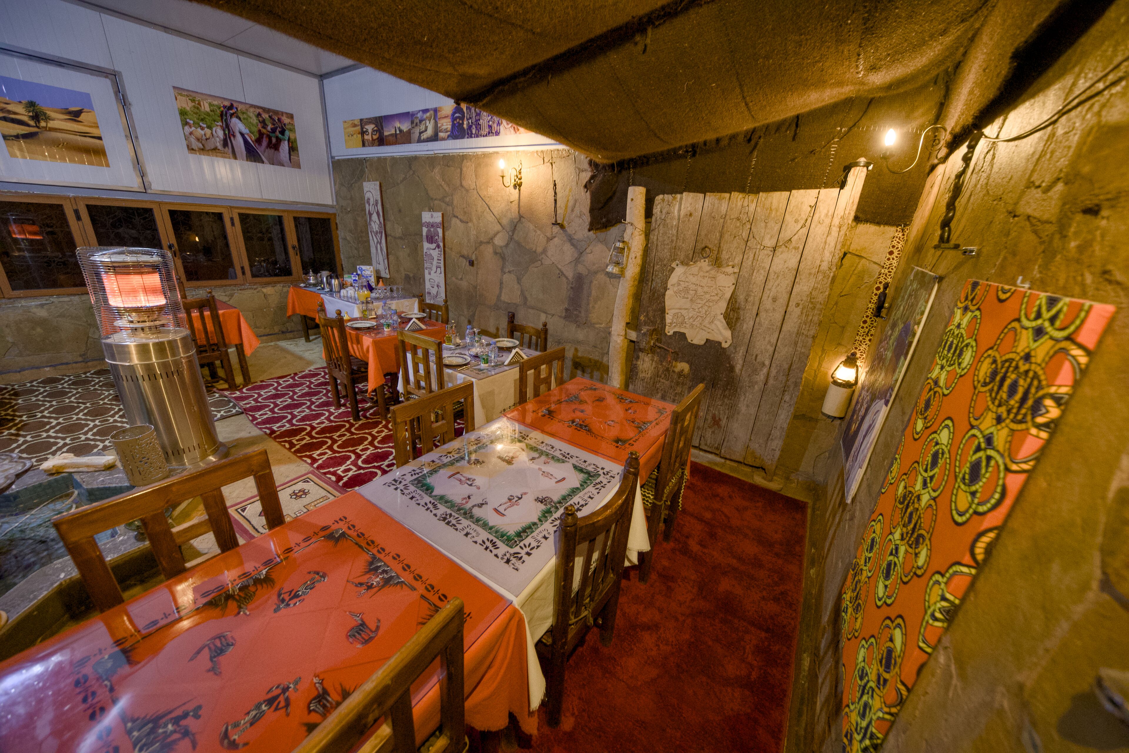 Ein Restaurant mit Holztischen und -stühlen, Steinwänden und Kunstwerken an den Wänden.