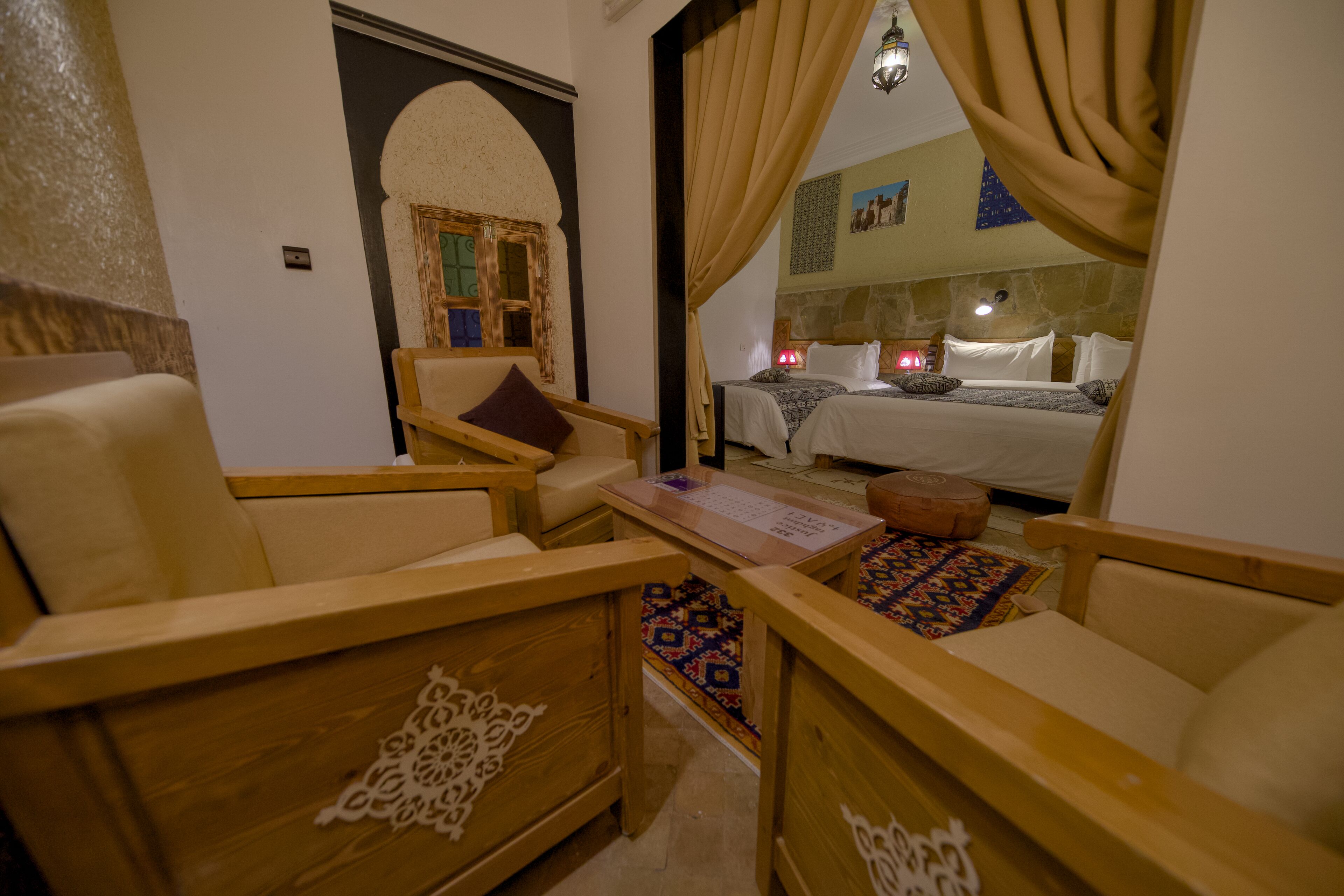 Una habitación tradicional con muebles de madera, una cama con ropa blanca y un tapiz estampado.