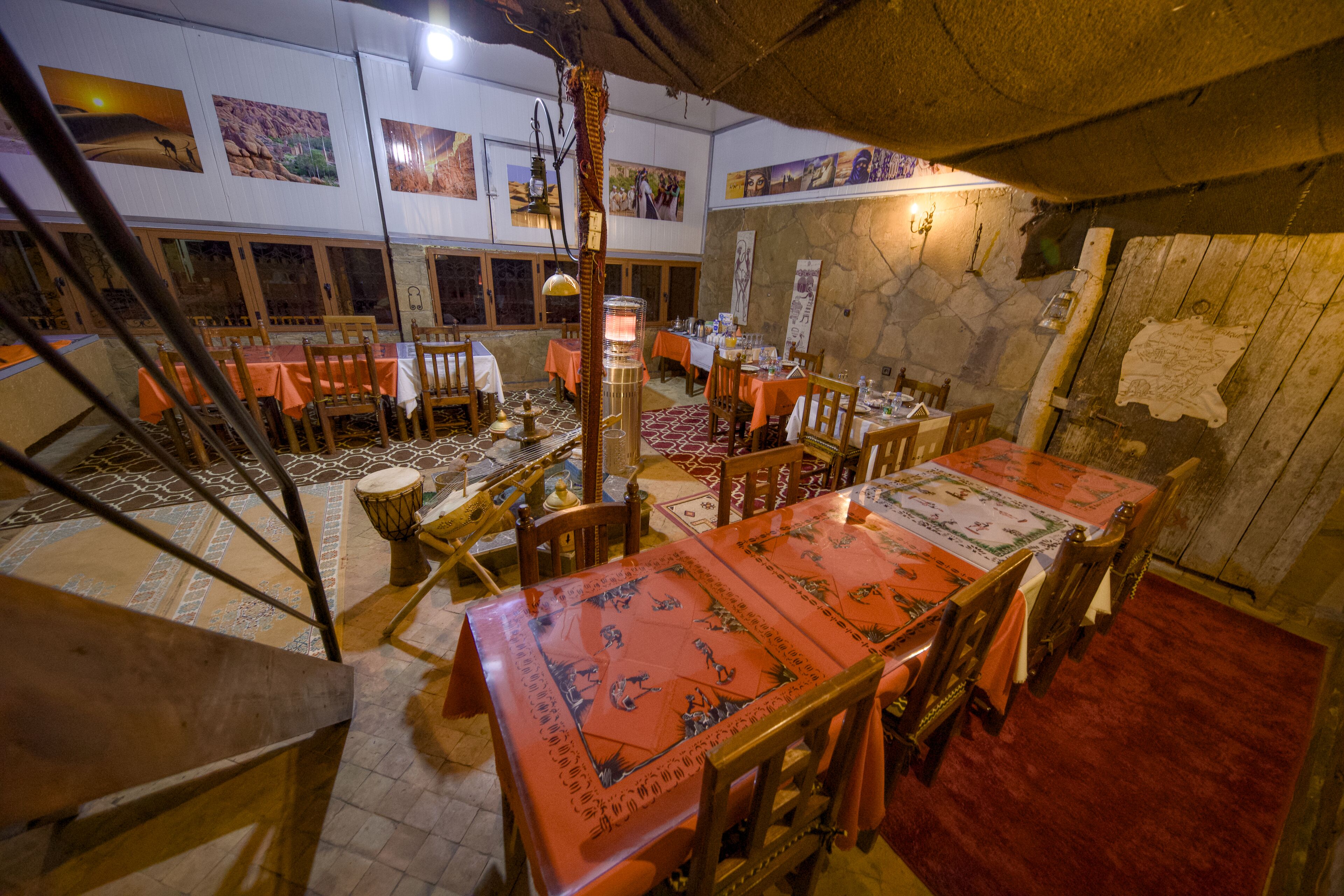 Un comedor con mesas dispuestas para varias personas, sillas de madera y una columna decorativa central.