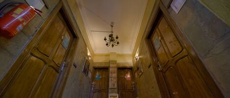 A hallway with wooden doors, a chandelier, and a patterned carpet.
