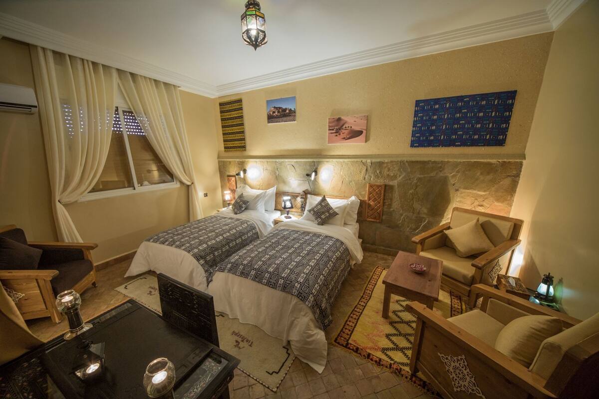 A hotel room with a double bed, two bedside tables, a desk, a chair, and a small rug.