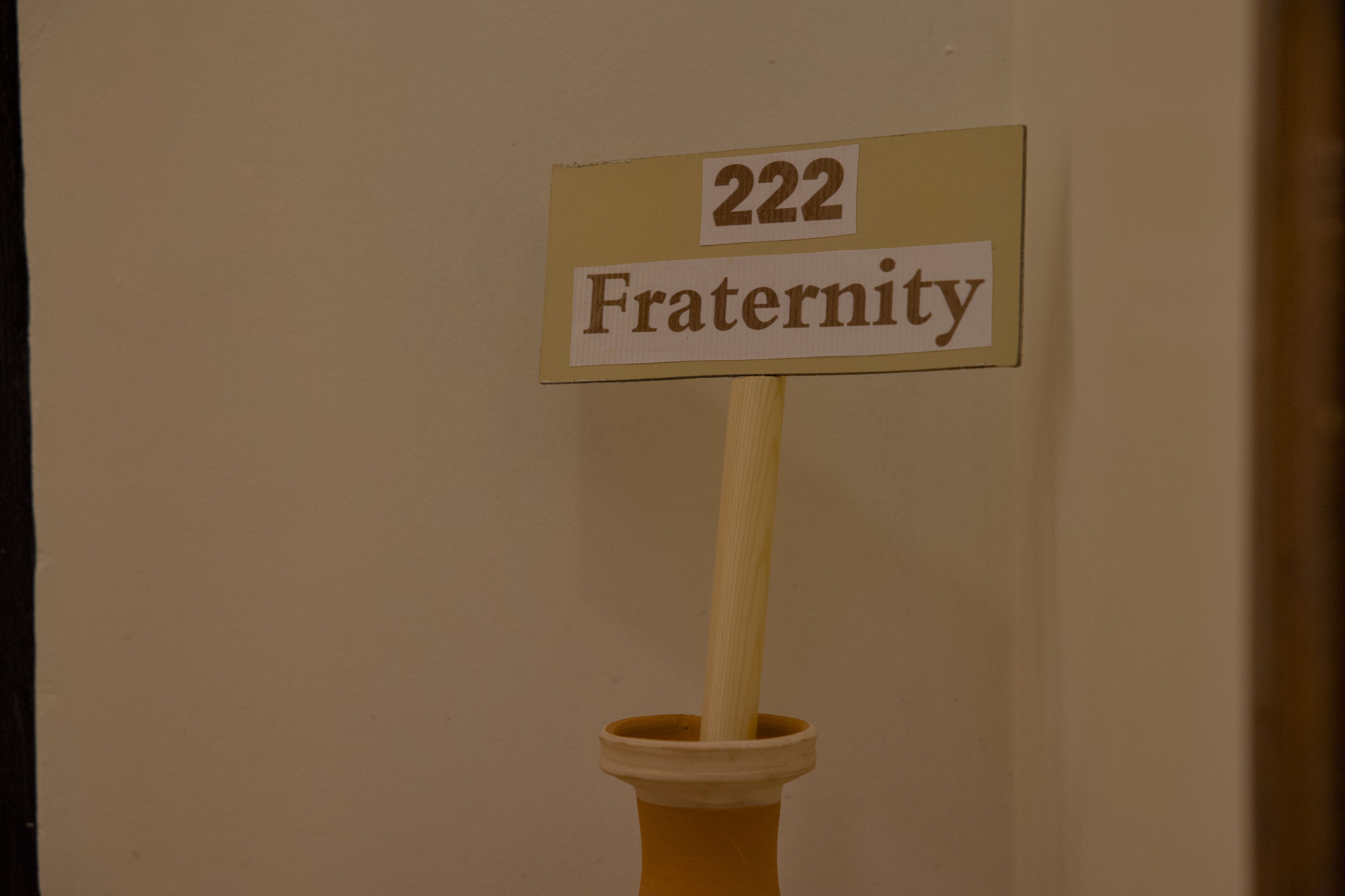 A sign with the number 222 and the word "Fraternity" on a wooden stick.