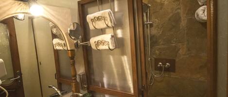 Une salle de bain avec un lavabo en marbre, une douche en verre et un luminaire encastré au plafond.