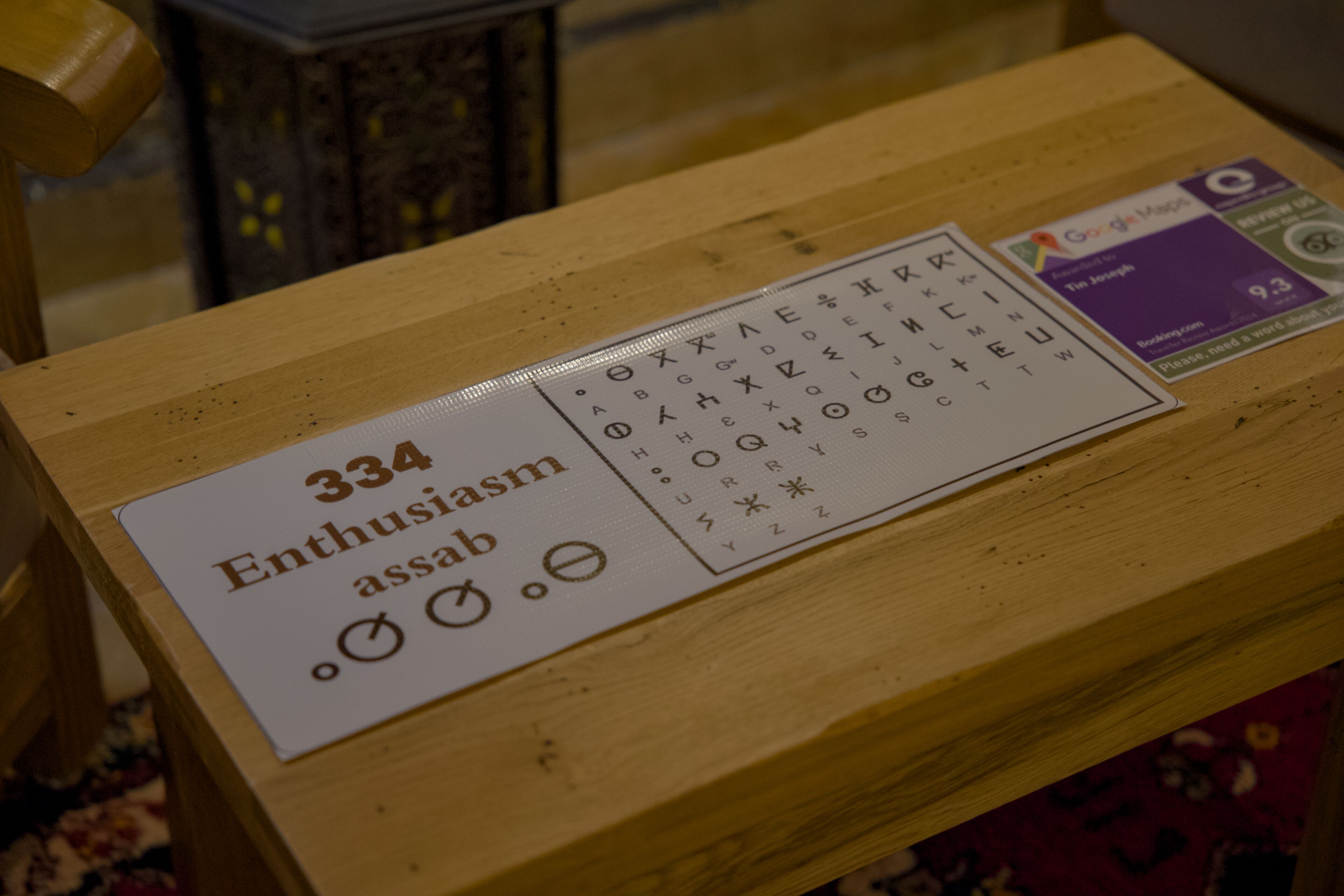 A wooden table with a sign reading "334 Enthusiasm assab" and a card with Google Maps logo.