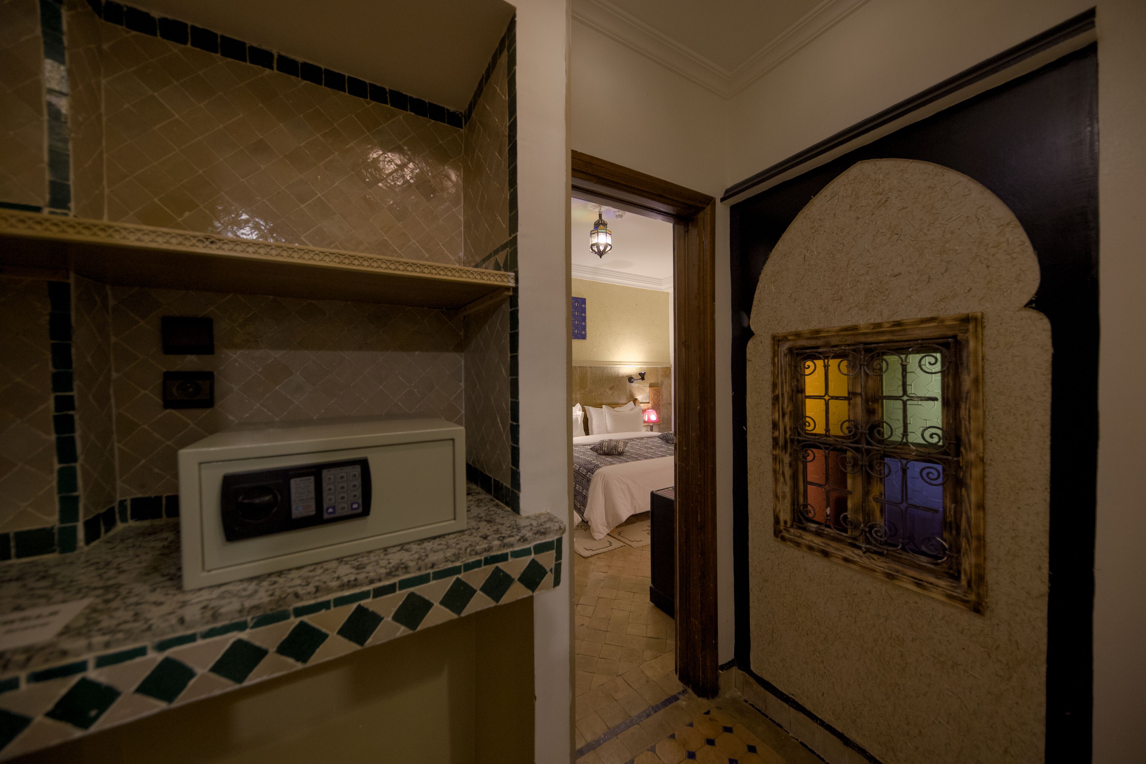 Una habitación de hotel con microondas en la encimera, una cama con mesita de noche y un ventanal decorativo de diseño único.